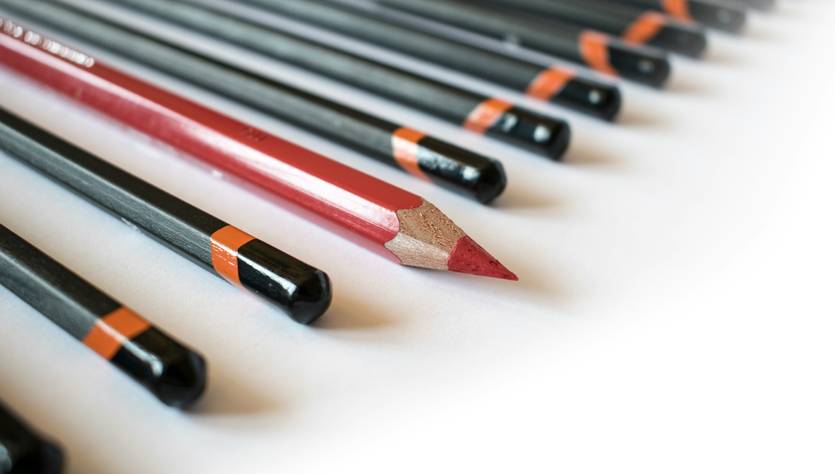 Un conjunto de lápices alineados con uno rojo en el centro.