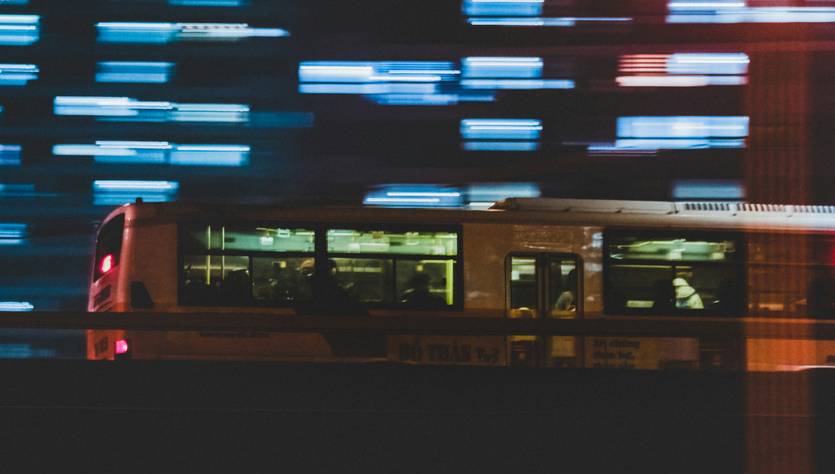 Una imagen de un autobús en movimiento, con luces difuminadas de fondo que crean un efecto de velocidad.