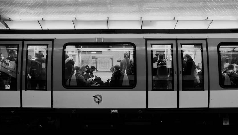 Una estación de metro con pasajeros visibles a través de las ventanas del tren.