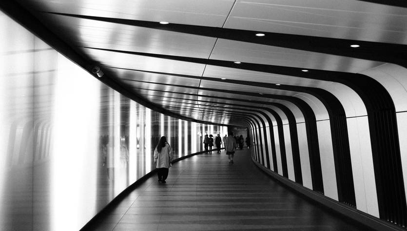 Un pasillo moderno y curvado con iluminación suave y personas caminando.