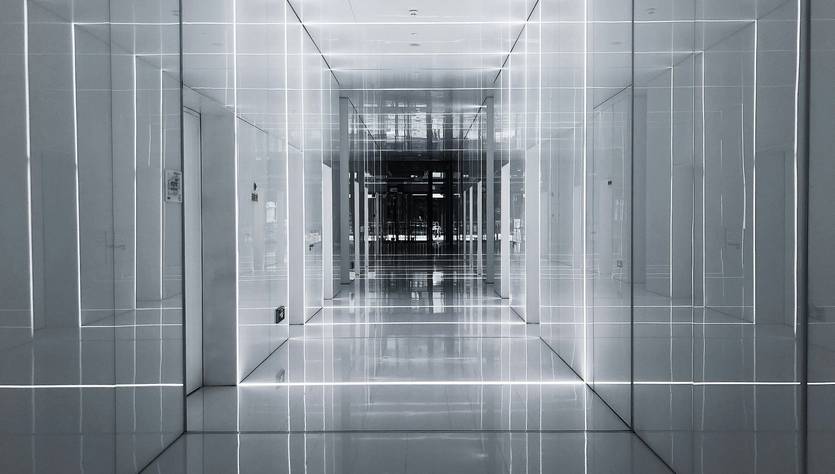 Un largo pasillo moderno con paredes blancas y luces integradas que crean un efecto futurista.