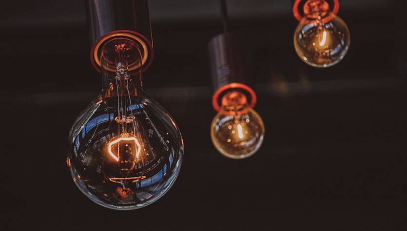 Tres bombillas colgantes iluminan un espacio con un diseño moderno y cálido.