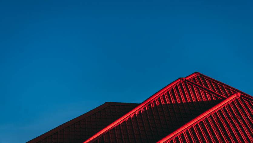 Una imagen de un tejado con luces rojas contra un cielo azul claro.