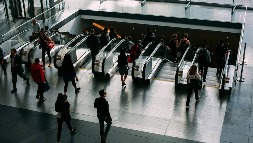 Una multitud de personas utiliza unas escaleras mecánicas en un edificio moderno.