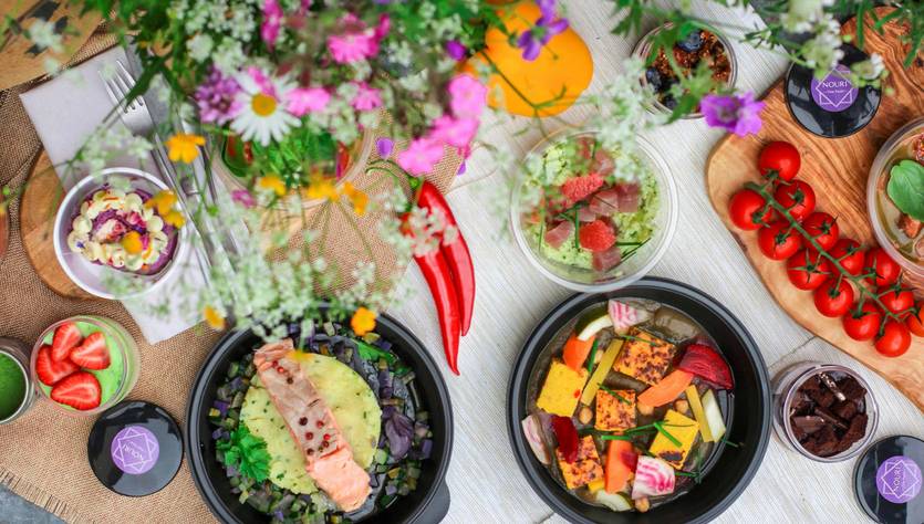 Una mesa elegantemente dispuesta con diversos platos de comida saludable y decorada con flores frescas.