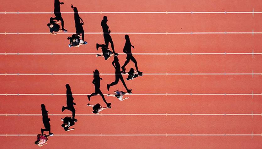 Un grupo de personas caminan sobre una pista de atletismo roja.