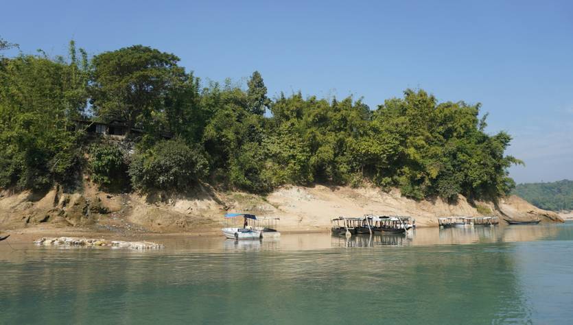 Una tranquila orilla de un río rodeada de vegetación y pequeños embarcaderos.