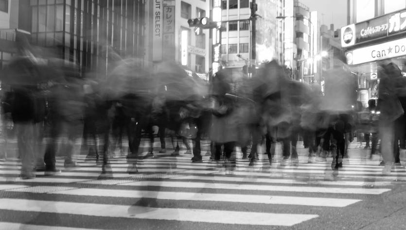 Una multitud de personas cruzando una calle en una escena urbana borrosa.