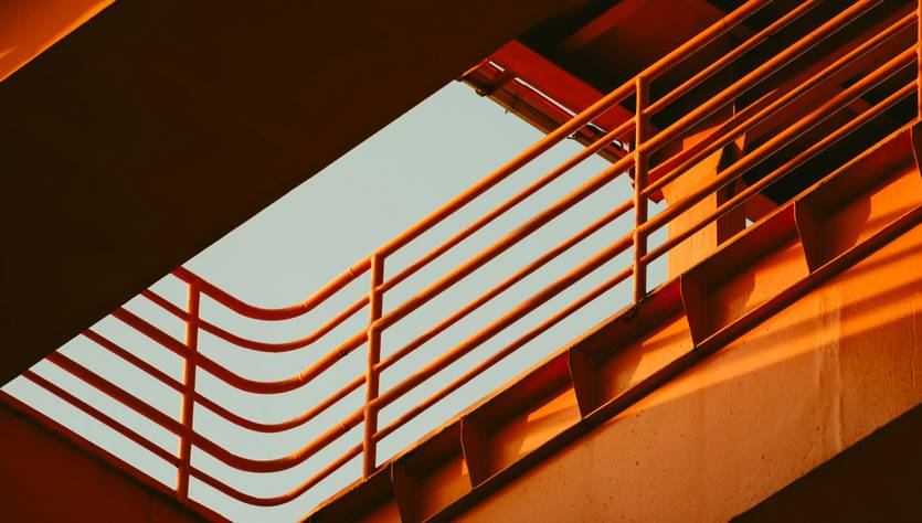 Una imagen abstracta que muestra líneas y sombras en tonos naranjas y un cielo azul en el fondo.