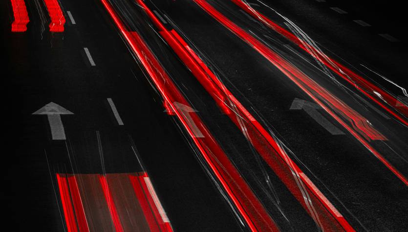 Una larga exposición de luces rojas y blancas en una carretera oscura.