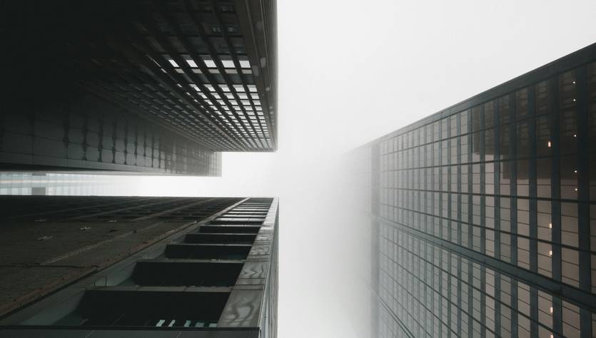 Una vista desde abajo de rascacielos en un día nublado y con niebla.