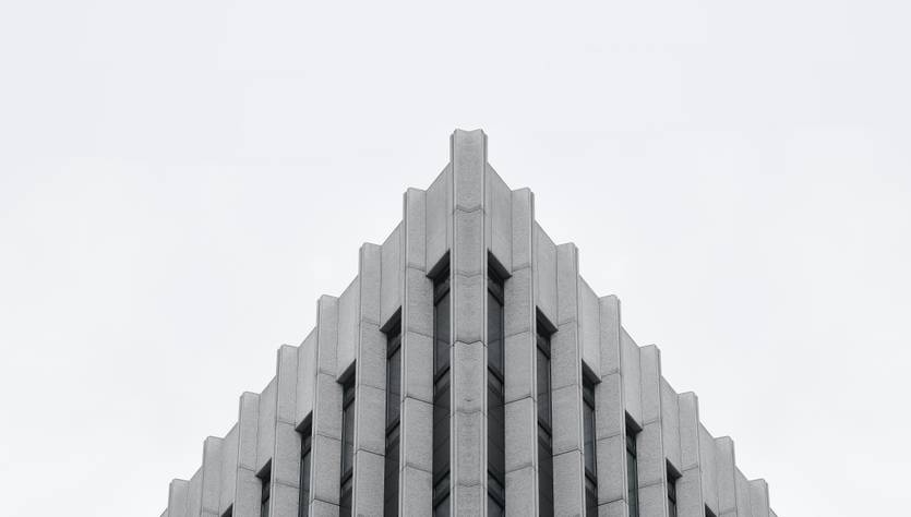 La imagen muestra la parte superior de un edificio moderno con un diseño angular y líneas verticales.