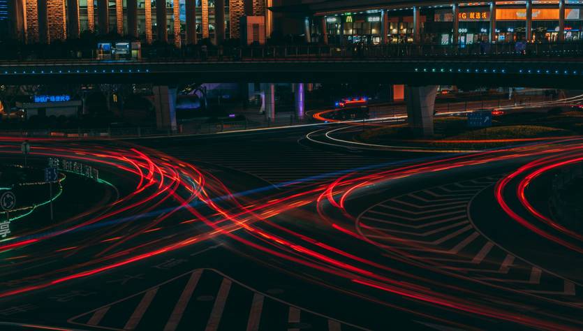 Una vista nocturna de una intersección con luces de coches formando un patrón dinámico.