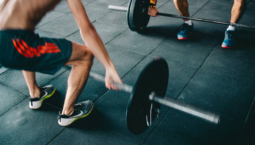 Dos personas levantando pesas en un gimnasio.