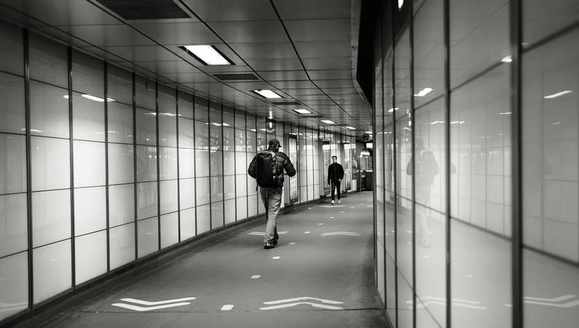 Un pasillo moderno y minimalista con personas caminando y paredes de vidrio.