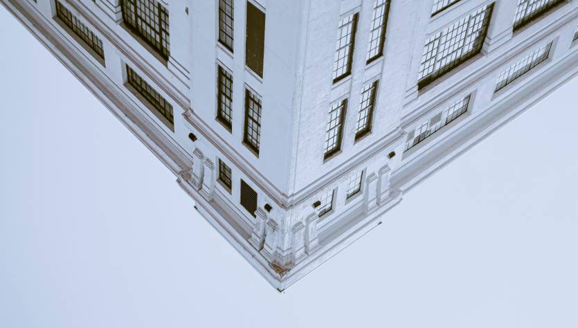 Una esquina de un edificio blanco con ventanas grandes en un fondo claro.