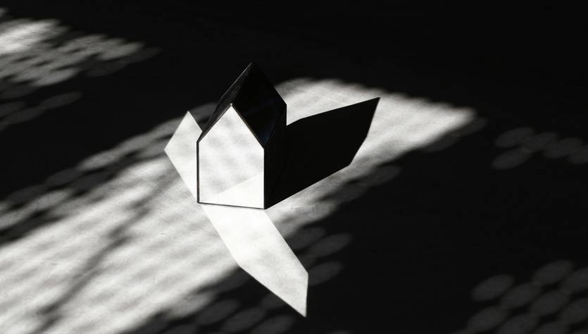 Un objeto en forma de casa proyecta sombras sobre una superficie iluminada.