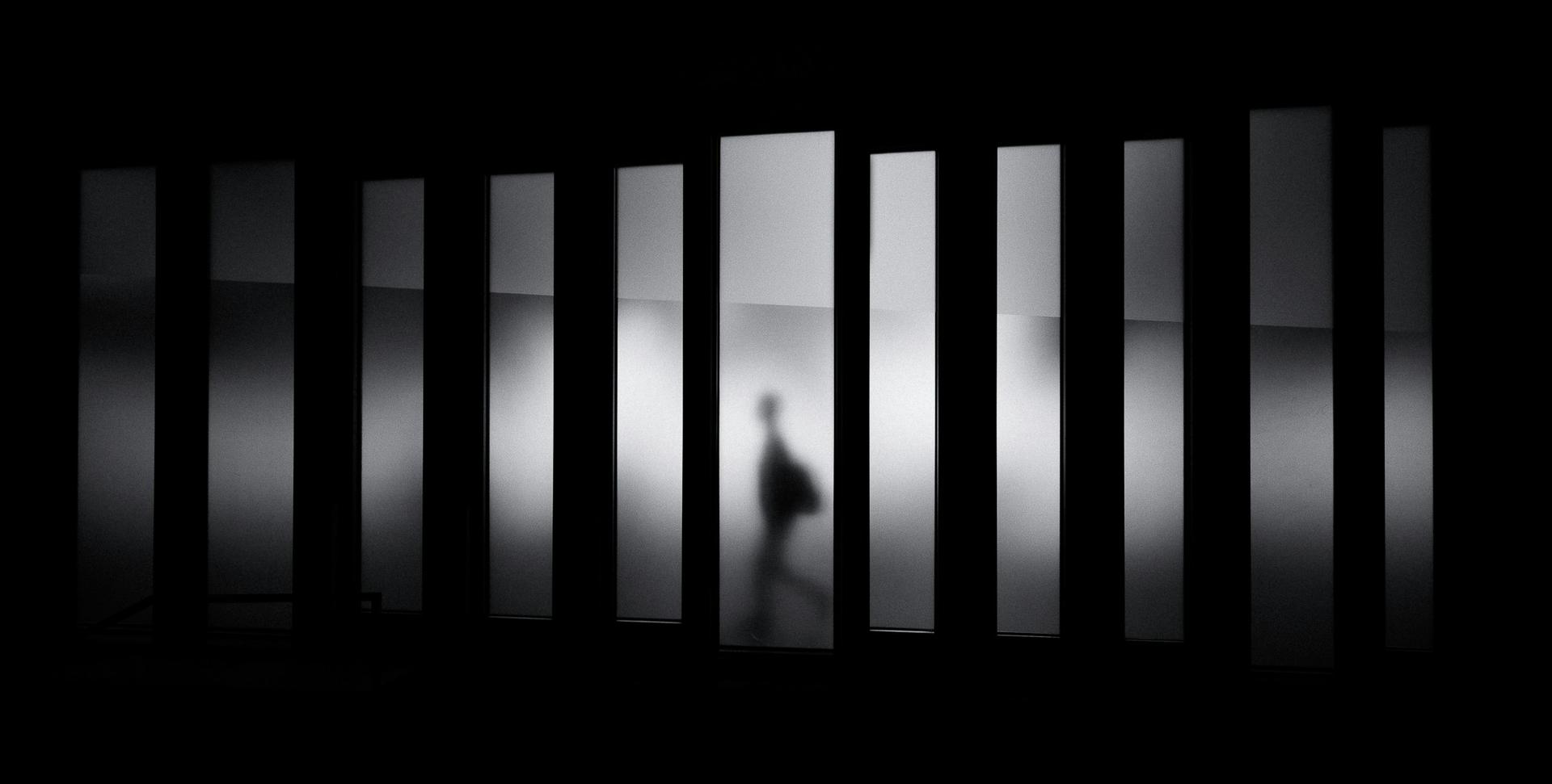 Una figura humana camina entre paneles iluminados en un entorno oscuro.