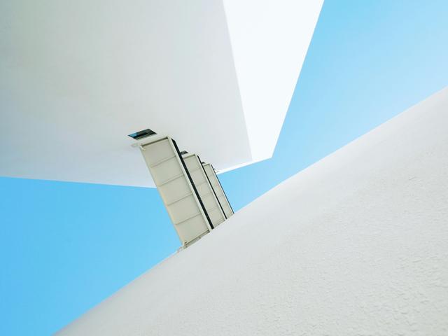 La imagen muestra una estructura arquitectónica moderna con un fondo de cielo azul claro.