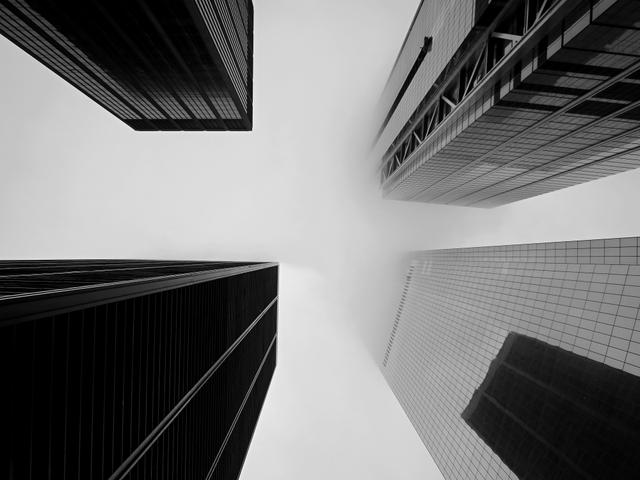 Una vista en blanco y negro de rascacielos desde abajo hacia arriba en un día nublado.