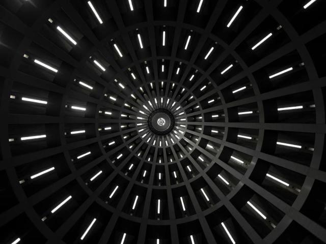 La imagen muestra un patrón circular con luces que emergen de un punto central en un fondo oscuro.