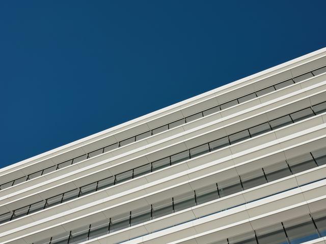 Una fachada moderna de un edificio con ventanas y un cielo azul claro.