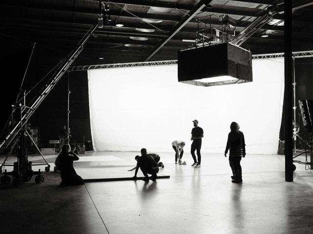 Un grupo de personas trabaja en un estudio de filmación con un fondo iluminado.