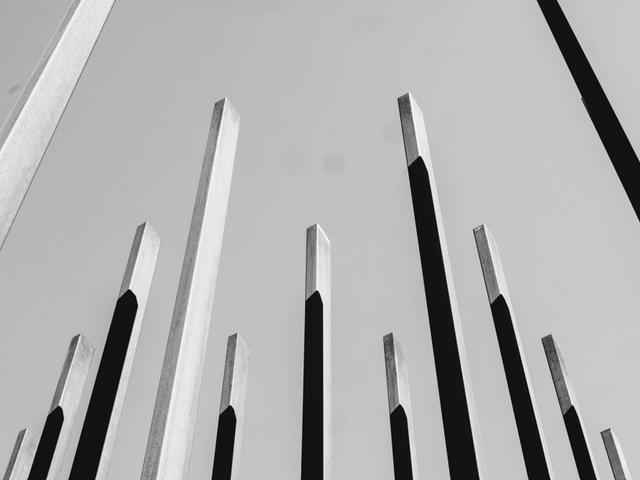 Una serie de estructuras verticales en tonos oscuros y claros que se elevan hacia el cielo.