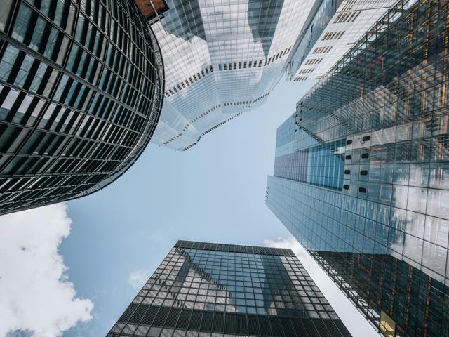 Una vista desde abajo de edificios modernos que reflejan el cielo.