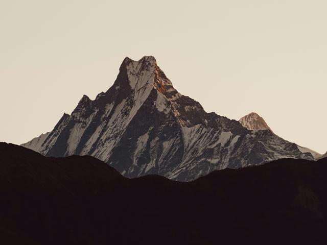 Una imponente montaña con picos nevados al atardecer.