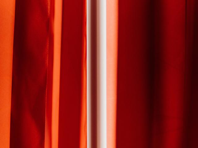 La imagen muestra una serie de cortinas rojas que crean un efecto dramático de color.