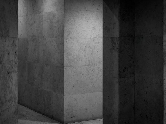 Un pasillo oscuro con paredes de piedra en tonos grisáceos.