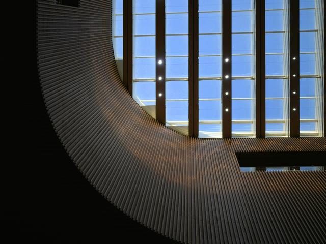 Imagen que muestra un diseño arquitectónico moderno con una estructura curvada y una gran ventana que permite la entrada de luz natural.