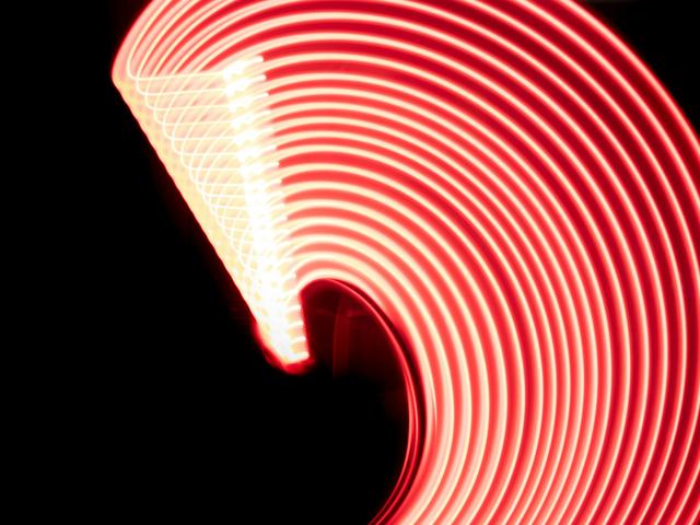 Una serie de luces rojas formando un arco luminoso sobre un fondo oscuro.