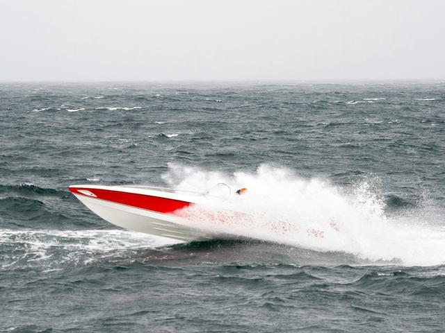 Un barco de motor surca las aguas agitadas del mar produciendo grandes olas.