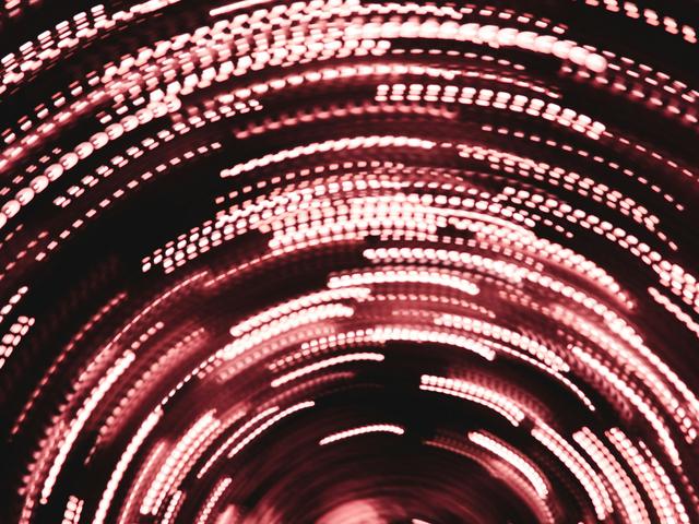 Una imagen abstracta con luces rojas en movimiento que crean un efecto de espiral.