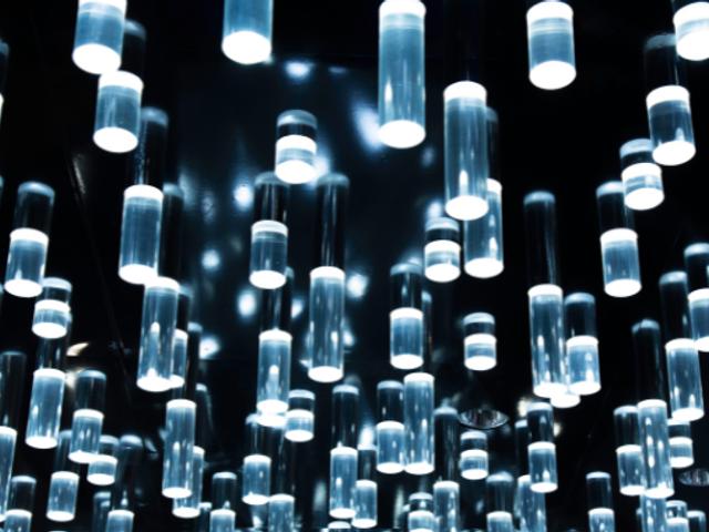 La imagen muestra una serie de luces colgantes en un fondo oscuro que crean un efecto visual atractivo.