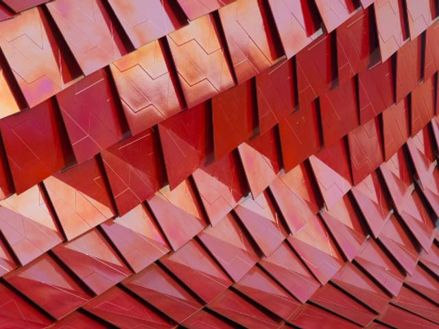 Una superficie compuesta por paneles en tonos rojos que crean un efecto tridimensional.
