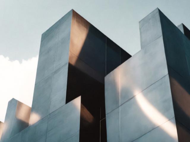 La imagen muestra un grupo de estructuras arquitectónicas modernas y angulares con un acabado metálico que refleja la luz.