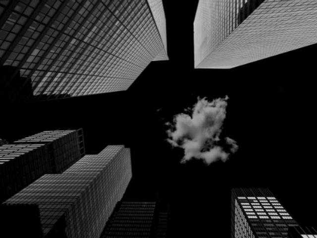 La imagen muestra un ángulo bajo de altos edificios rodeando un cielo oscuro con una nube blanca.