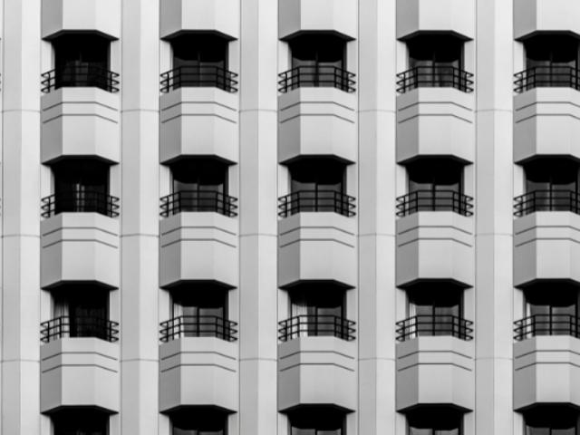 Imagen en blanco y negro de un patrón repetitivo de ventanas de un edificio moderno.