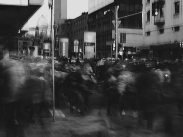 Una multitud de personas se mueve en una calle urbana en un ambiente borroso.