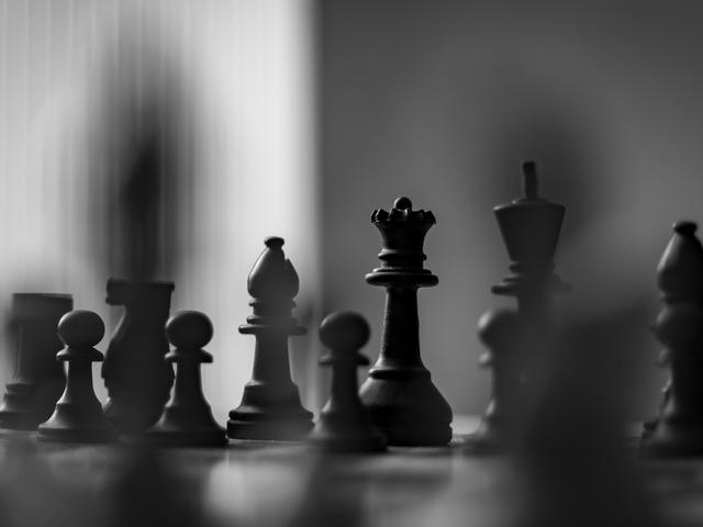 Una partida de ajedrez en blanco y negro con piezas de diferentes formas alineadas en el tablero.