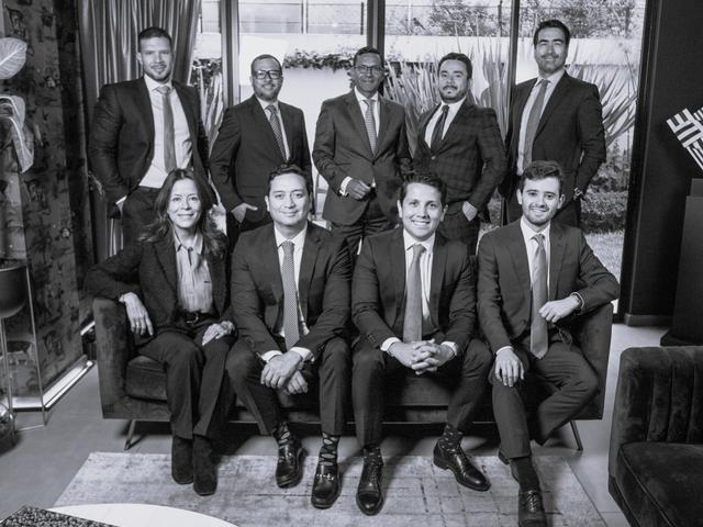 Un grupo de diez personas vestidas de manera formal posan en una sala moderna.