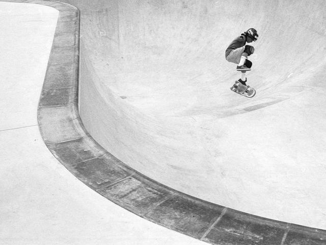 Un skater realiza un truco en un bowl de patinaje en una imagen en blanco y negro.