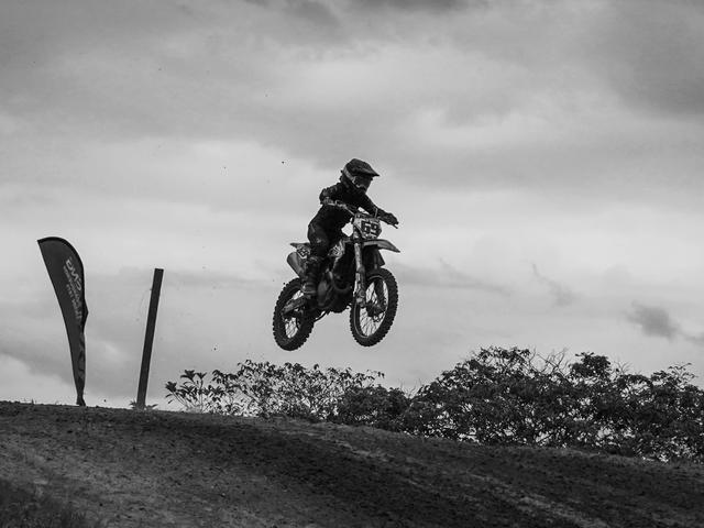 Un motociclista realiza un salto en una pista de motocross en un entorno natural.