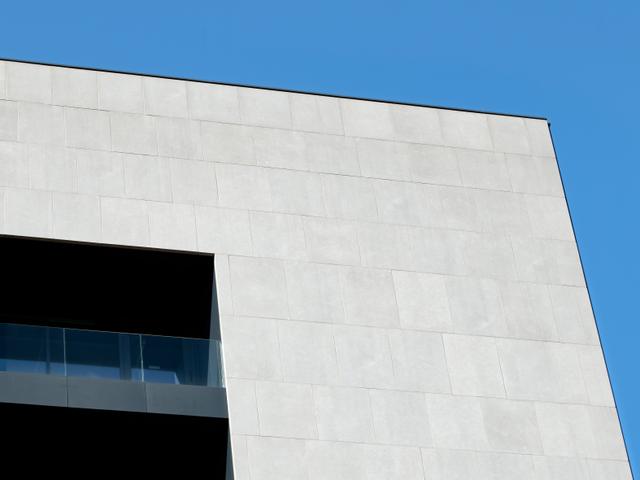 Un edificio moderno con una fachada blanca y un ventanal en la parte superior.