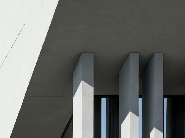 La imagen muestra una estructura arquitectónica moderna con líneas geométricas y sombras marcadas.