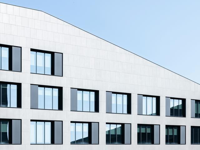 Edificio moderno con una fachada asimétrica y ventanas lineales.