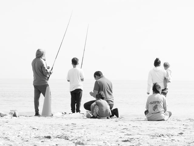 Un grupo de personas pesca en la playa frente al mar.